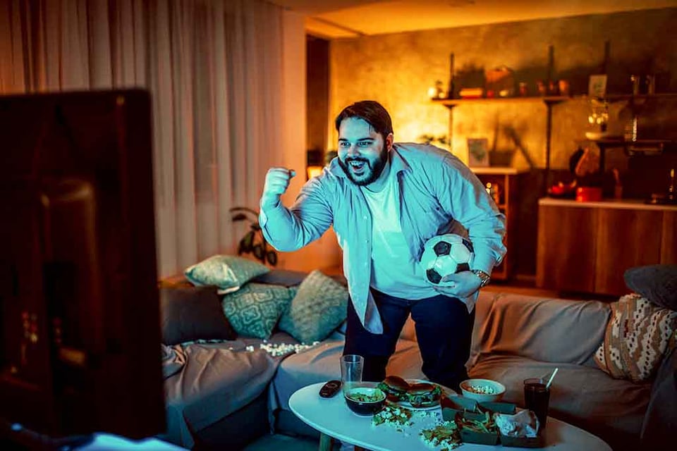 hombre viendo un partido de fútbol en casa