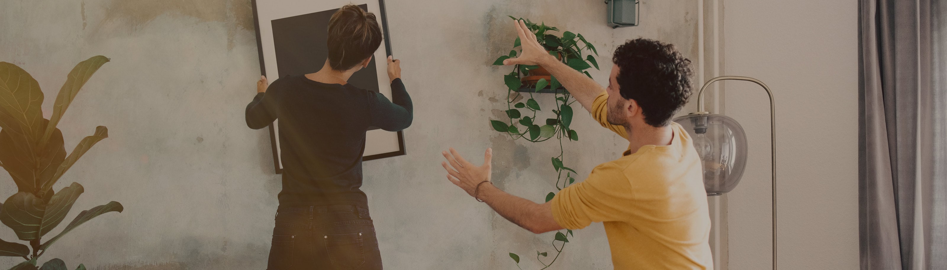 pareja joven acomodando un cuadro en su hogar