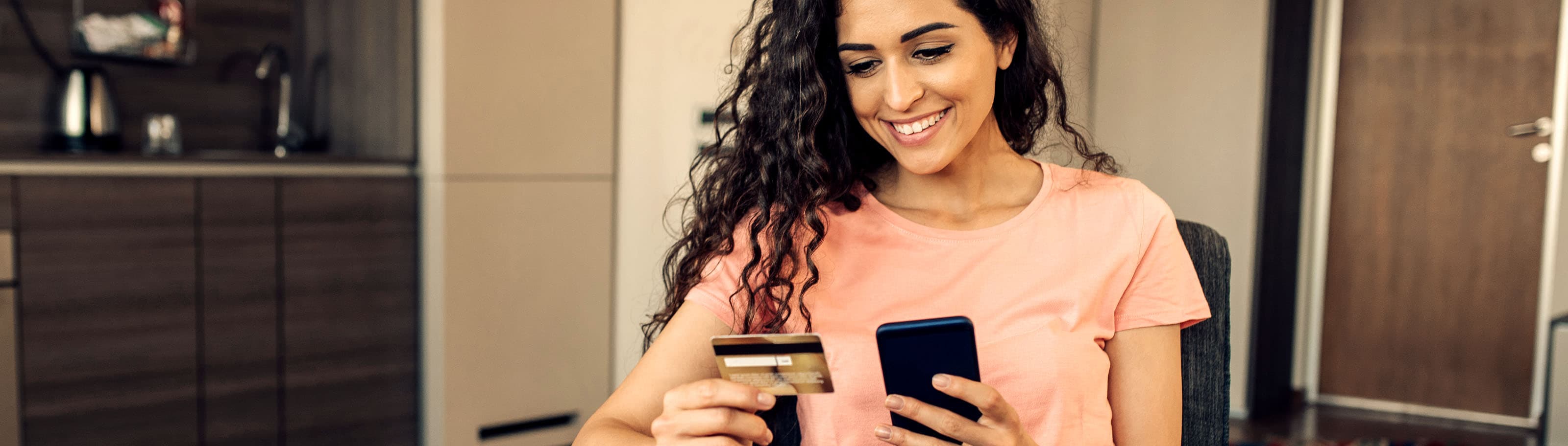 mujer viendo su celular y tarjeta de débito
