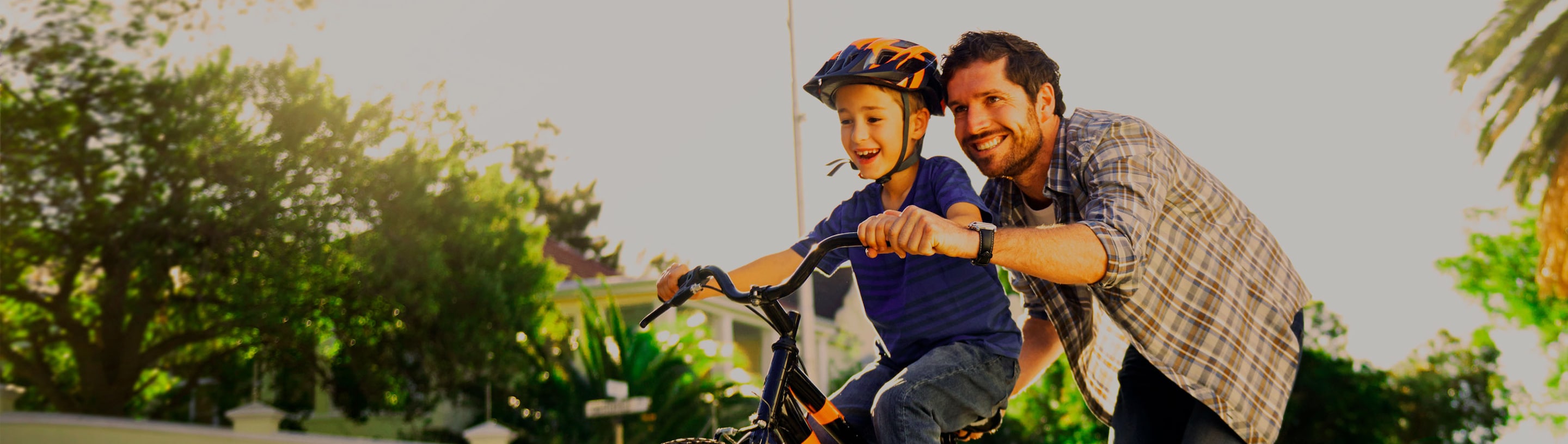 Papa-ensenando-andar-bici-hijo-casco-sonriendo