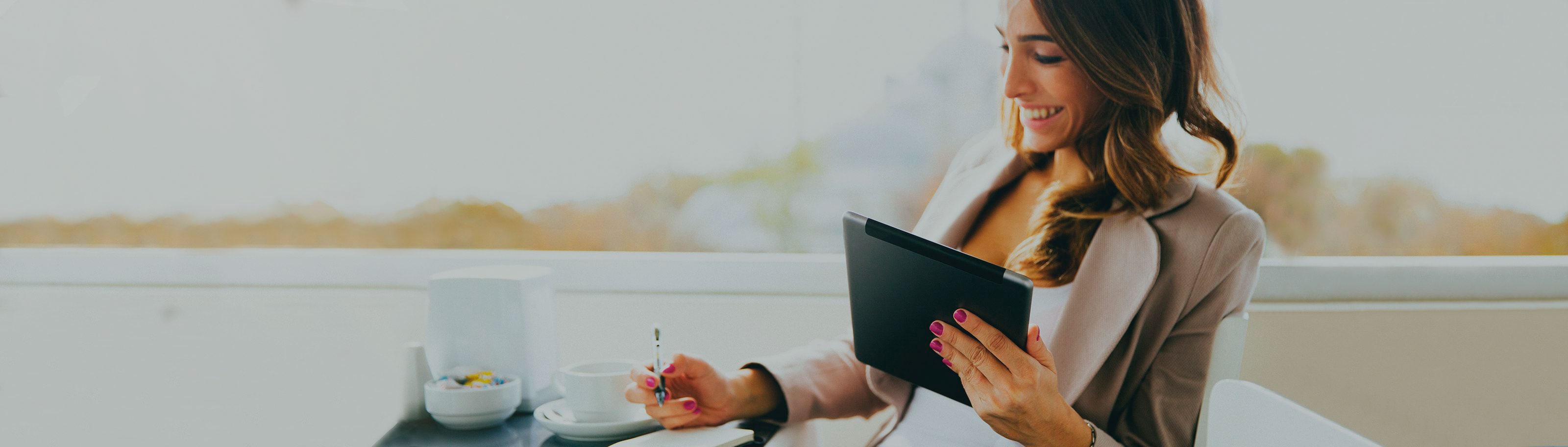 Mujer sonriendo tomando cafe realizando pagos desde su tablet