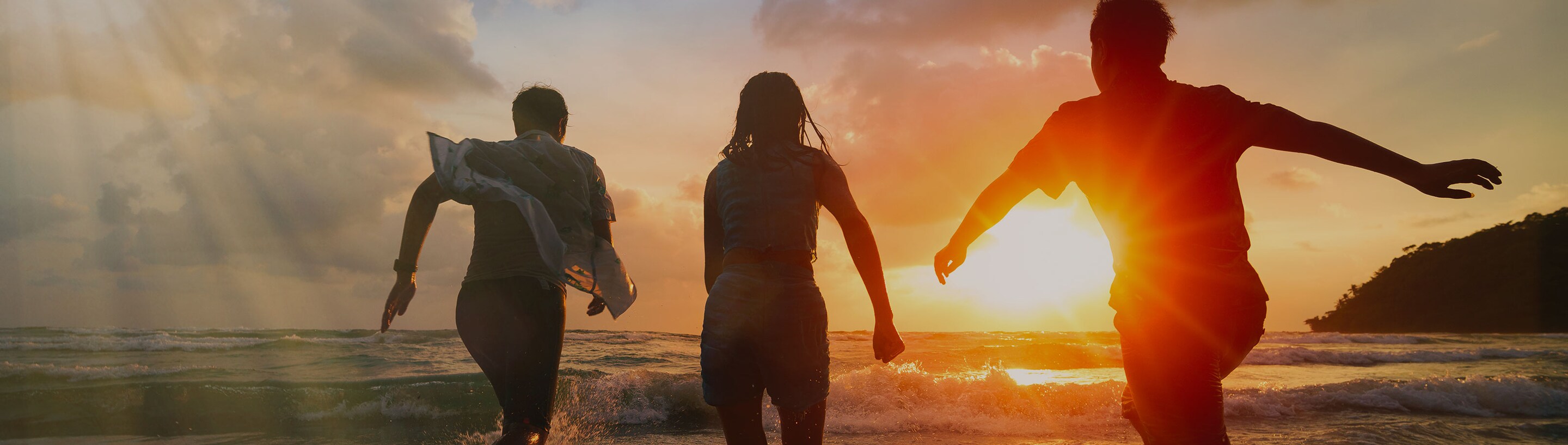 jóvenes en la playa corriendo en un atardecer
